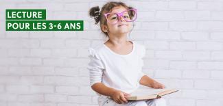 enfant assis avec grosses lunettes et livre sur les genoux